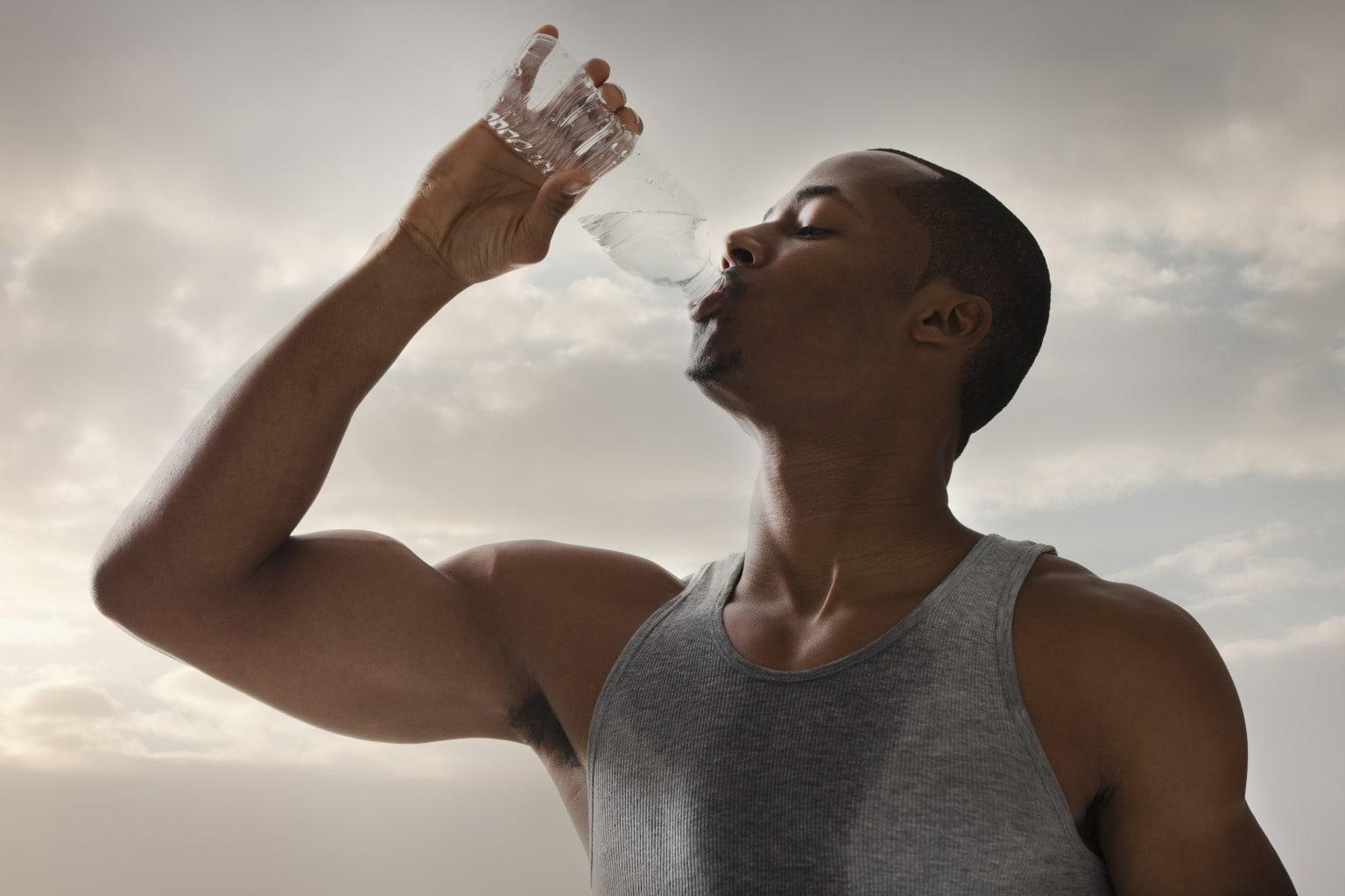 Капли пота на лбу. Вспотевший спортсмен. Спортсмен пьет воду. Парень пьет воду. Потоотделение в жару.